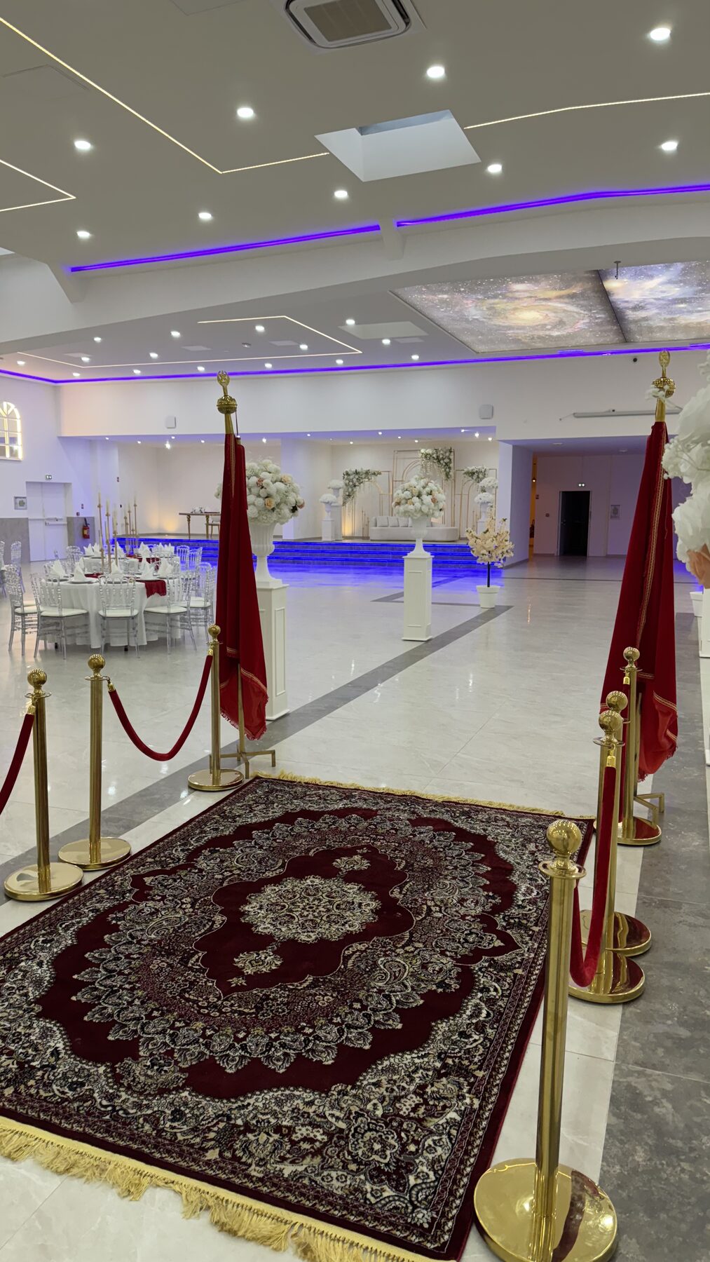 Allée cérémonielle avec tapis rouge et urnes florales au Festif