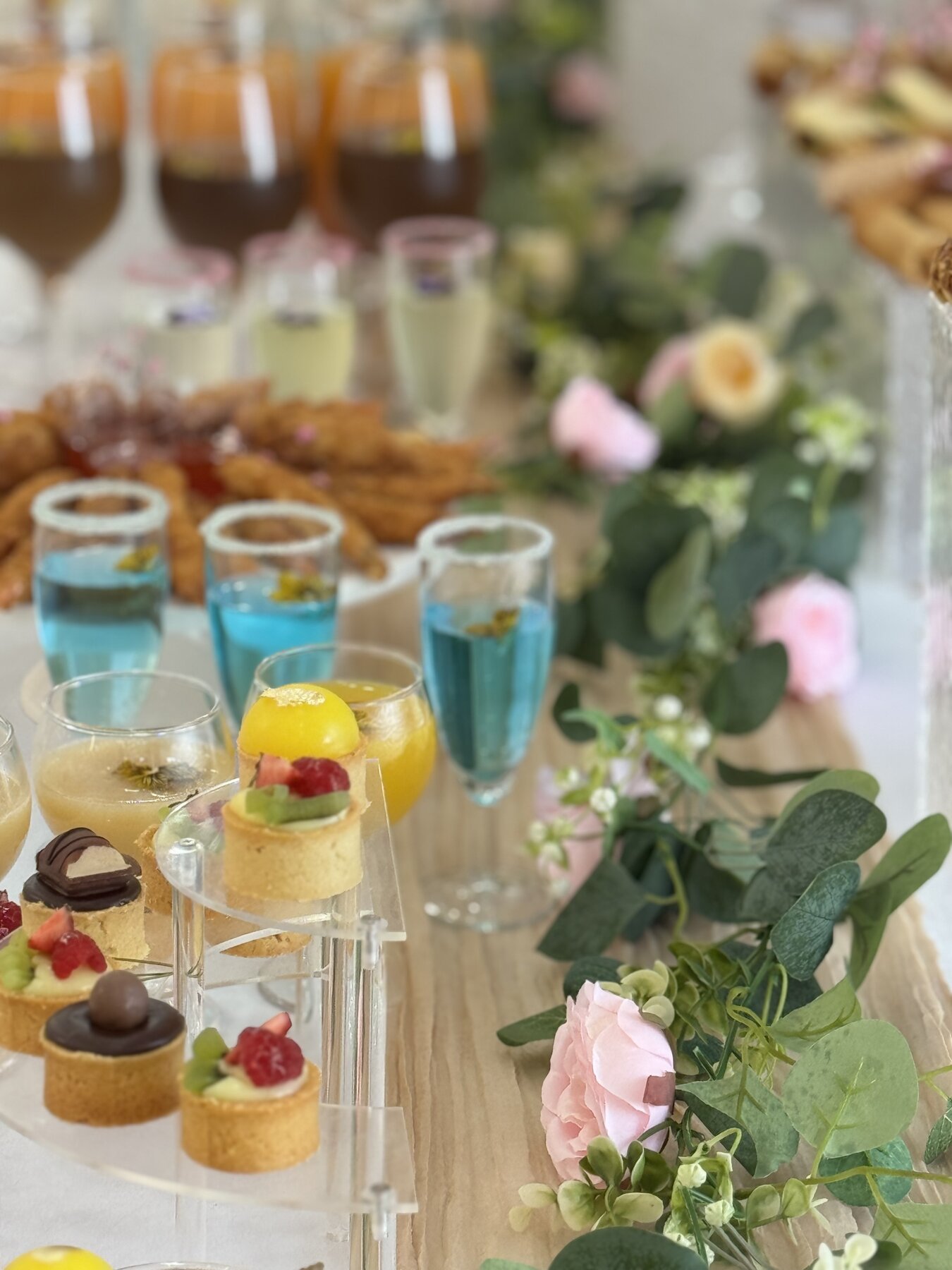 Table cocktail fleurie avec boissons et pièces sucrées pour réception au Festif